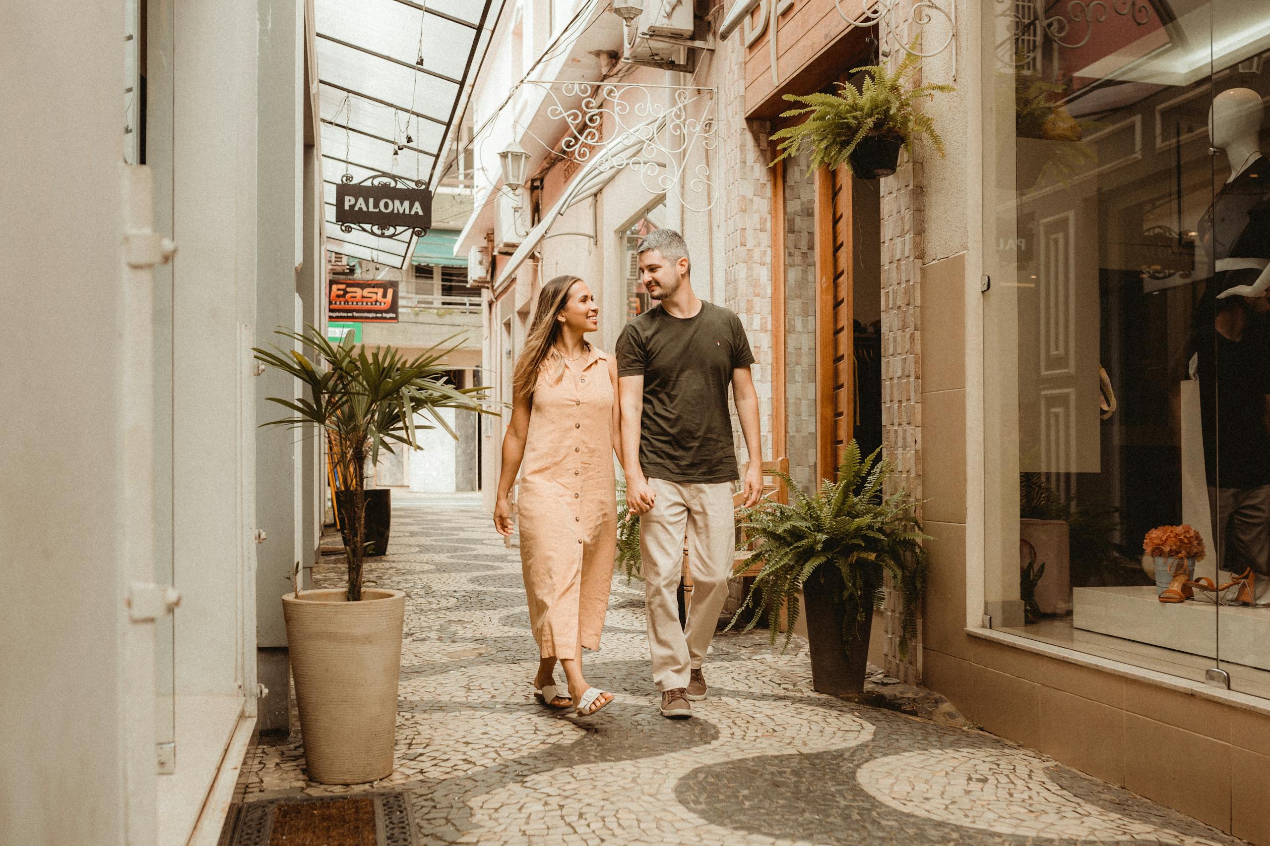 Joyful couple walking hand in hand through charming city alley with shops.