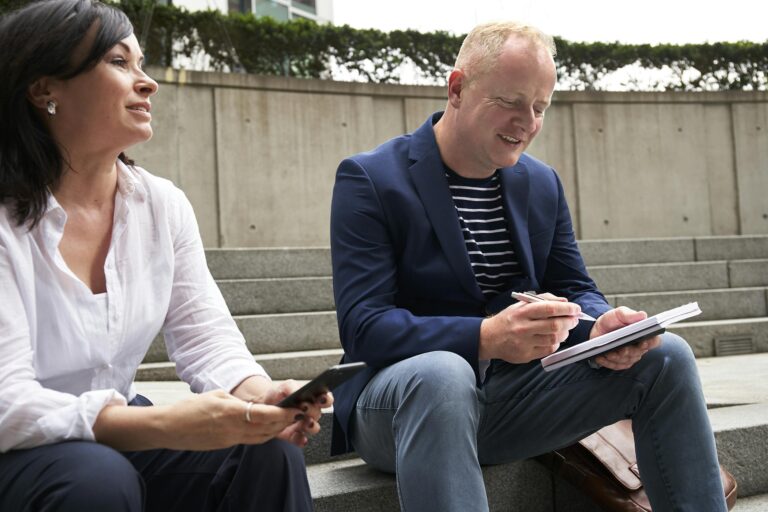 Man and woman engaged in work-related discussion outdoors in London setting.