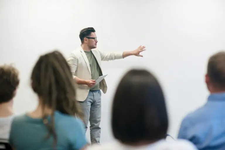 Man in blazer giving presentation to engaged audience in lecture hall setting