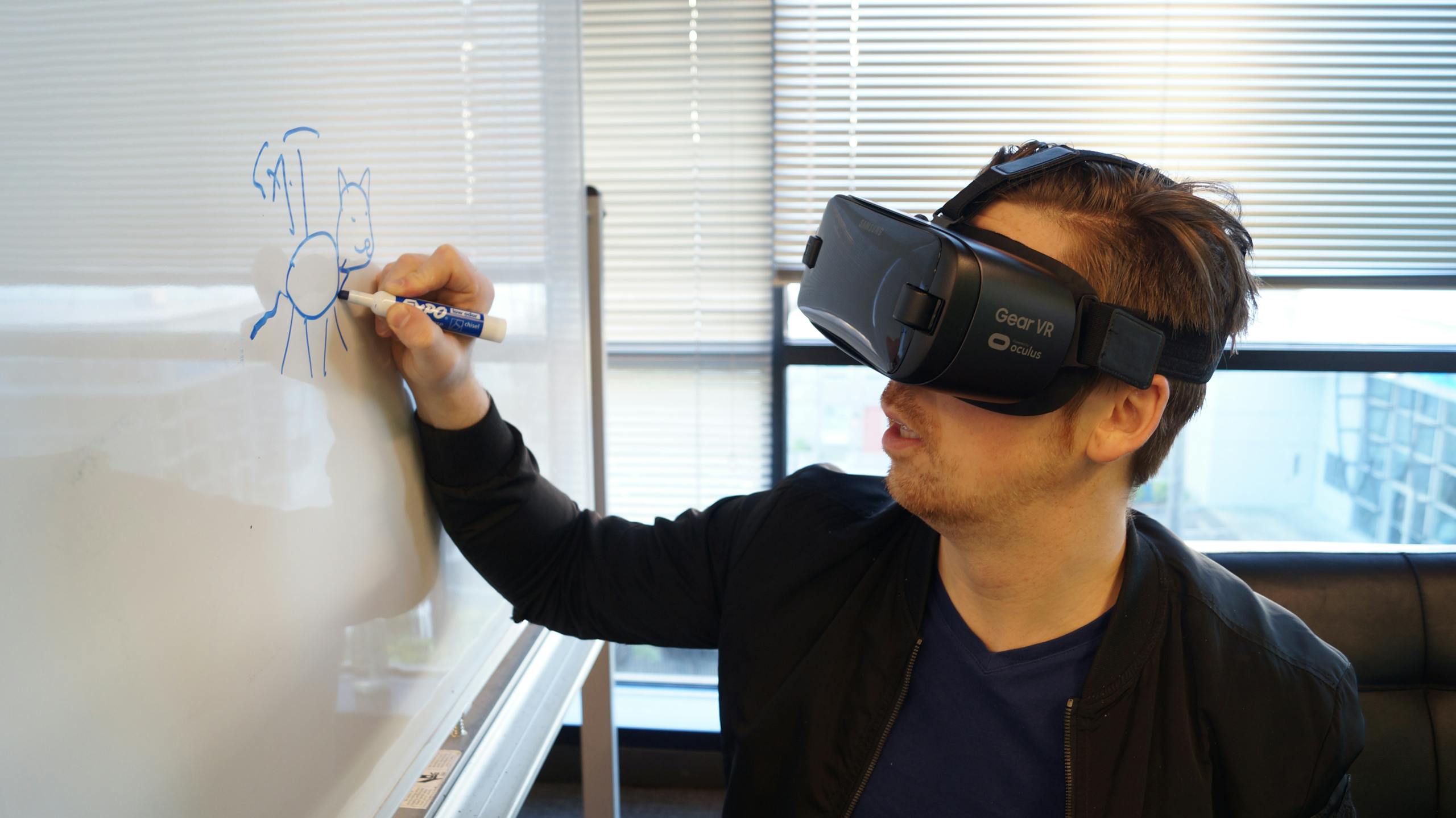 Man wearing VR headset drawing cat on whiteboard in office