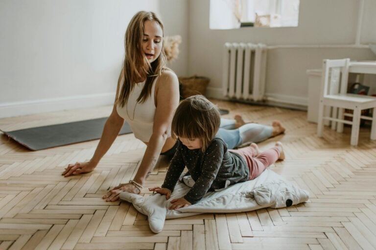 Mother and child practicing yoga together at home on sunny day