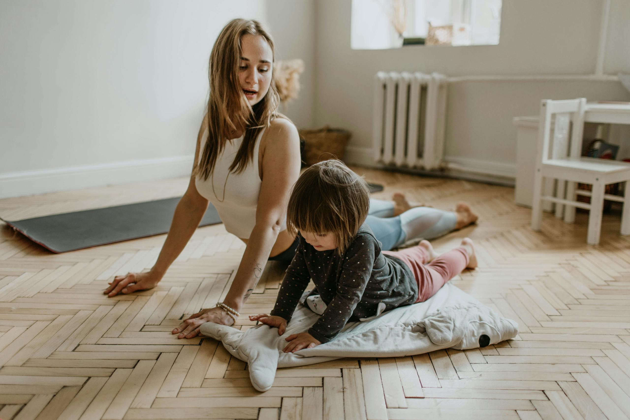 Mother and child practicing yoga together at home on sunny day
