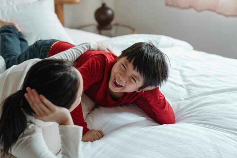 Mother and son lying on bed sharing a joyful moment filled with laughter and love.