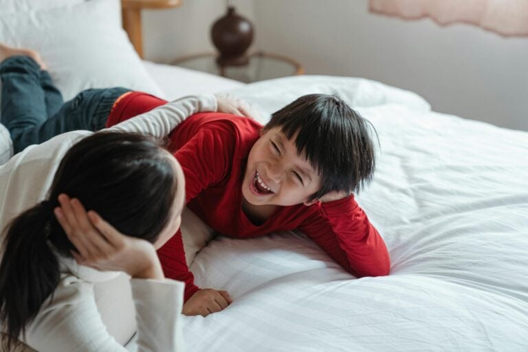 Mother and son lying on bed sharing a joyful moment filled with laughter and love.