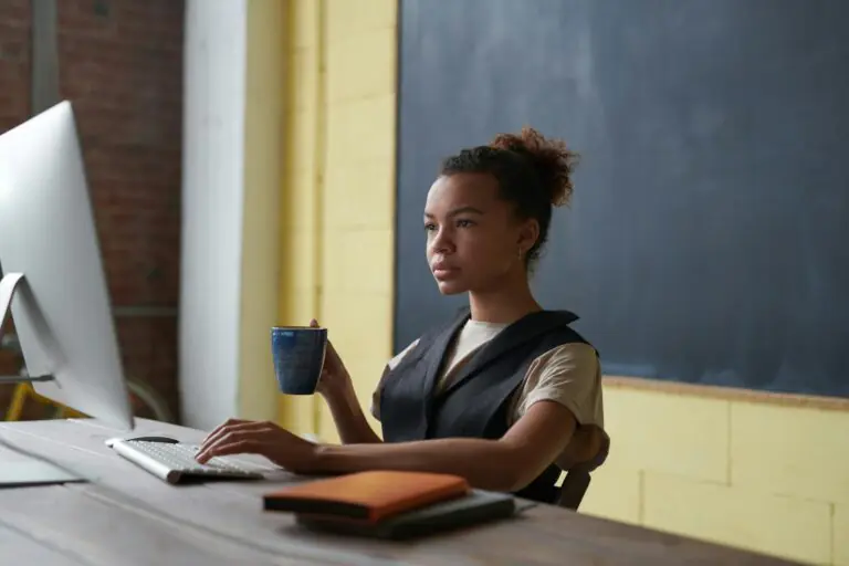 Professional young woman concentrating on work at desk with computer and coffee