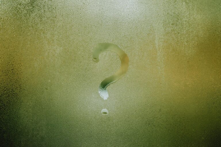 Question mark drawn on foggy glass surface evoking uncertainty and curious introspection