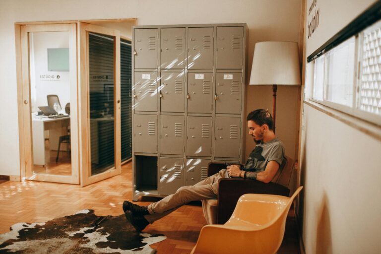 Relaxed man sits in contemporary office featuring lockers and stylish furniture creating cozy workspace