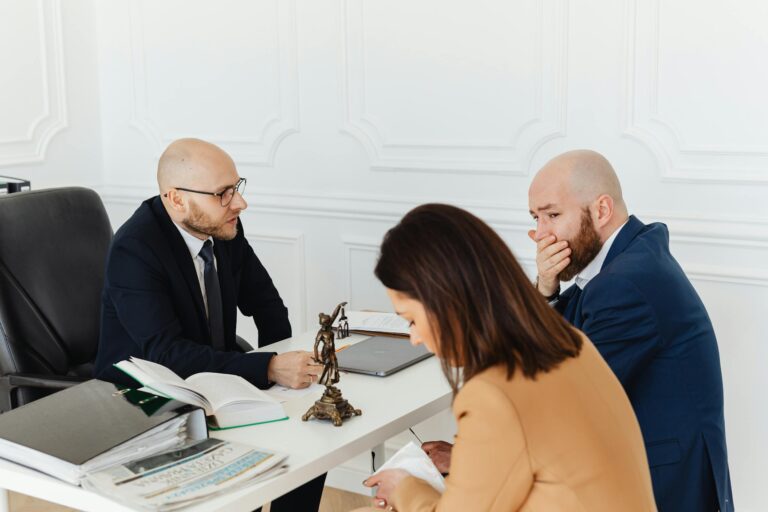 Three adults in serious legal consultation discussion in professional office environment