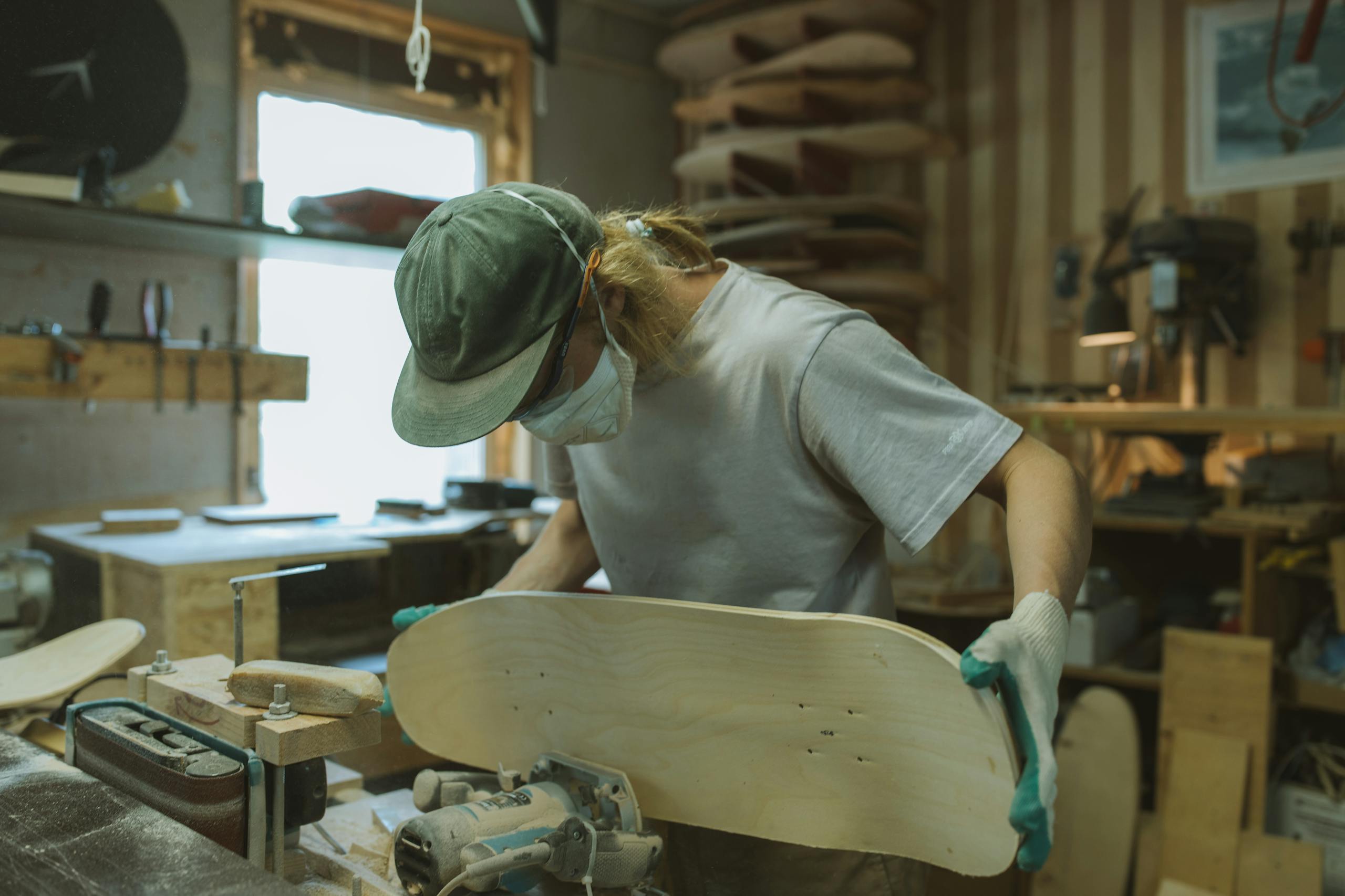 Skilled craftsman using router to shape skateboard deck in workshop setting.
