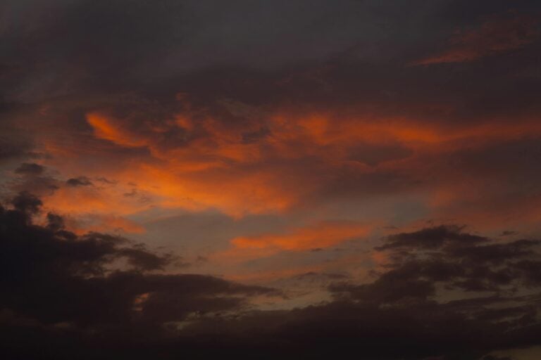 Stunning and dramatic sunset with red and gray clouds in evening sky.