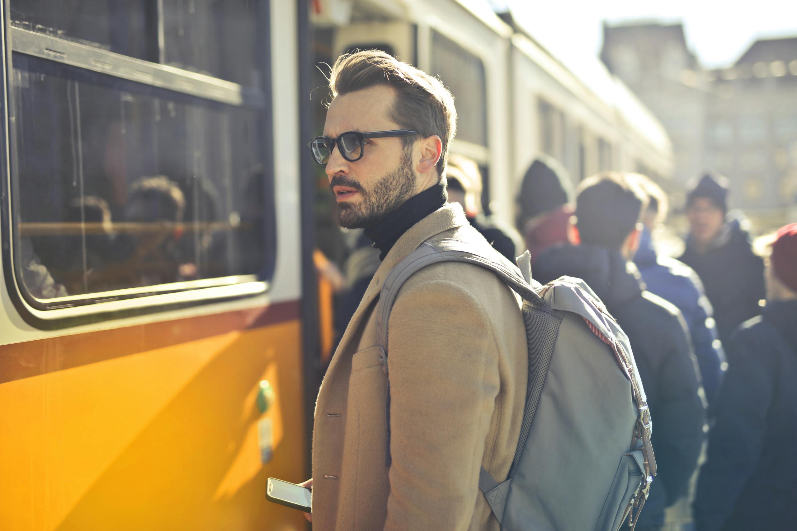 Stylish man with backpack boards tram in bustling Budapest city.