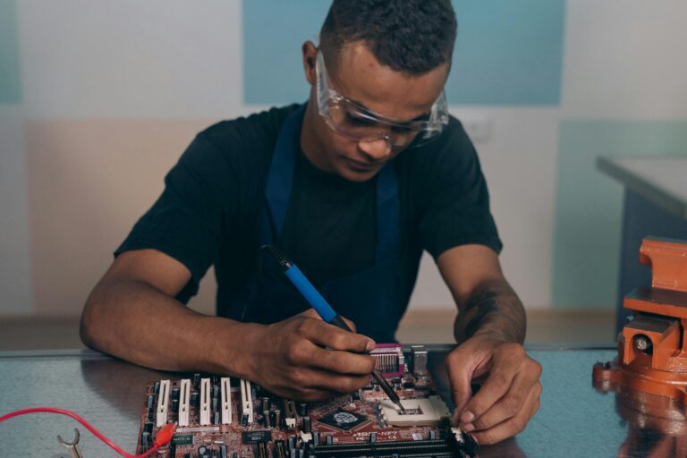Technician wearing safety glasses working intently on computer motherboard