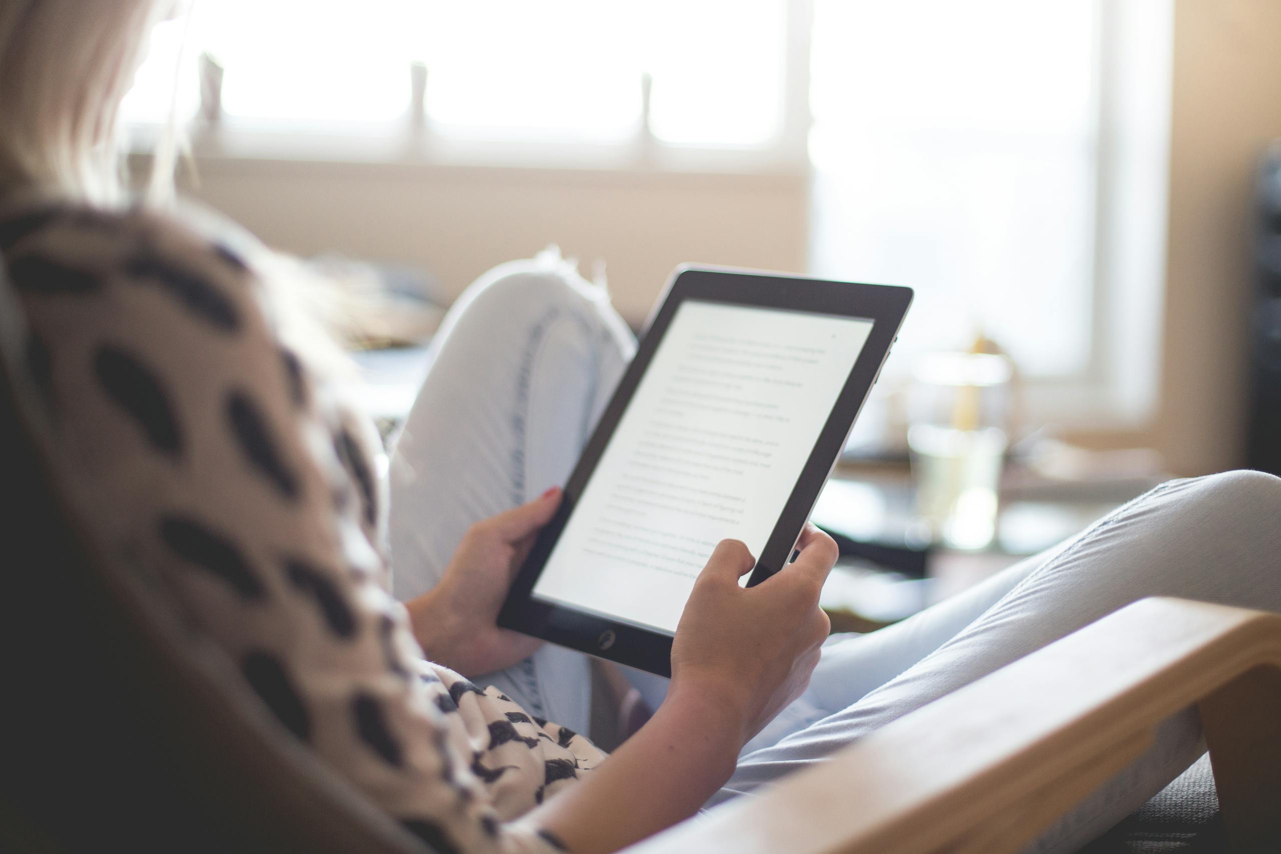 Woman enjoying reading on tablet comfortably in modern living room