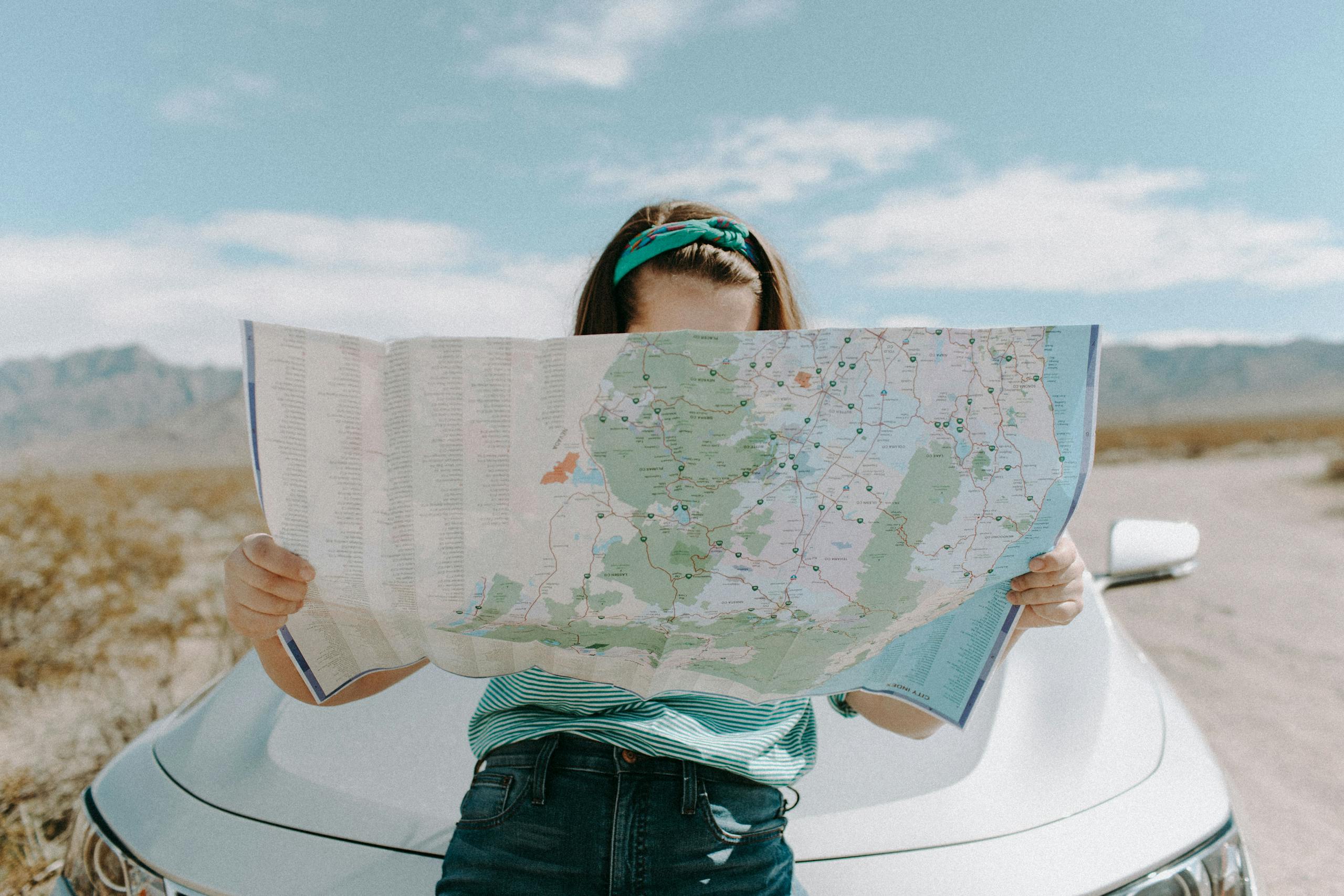 Woman holding map while traveling through scenic California desert.