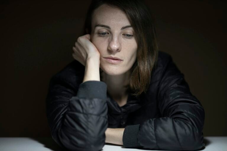 Woman in serious thought indoors under low, moody lighting conditions