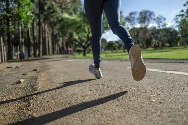 Woman running outdoors on sunny day along scenic park trail focusing on fitness