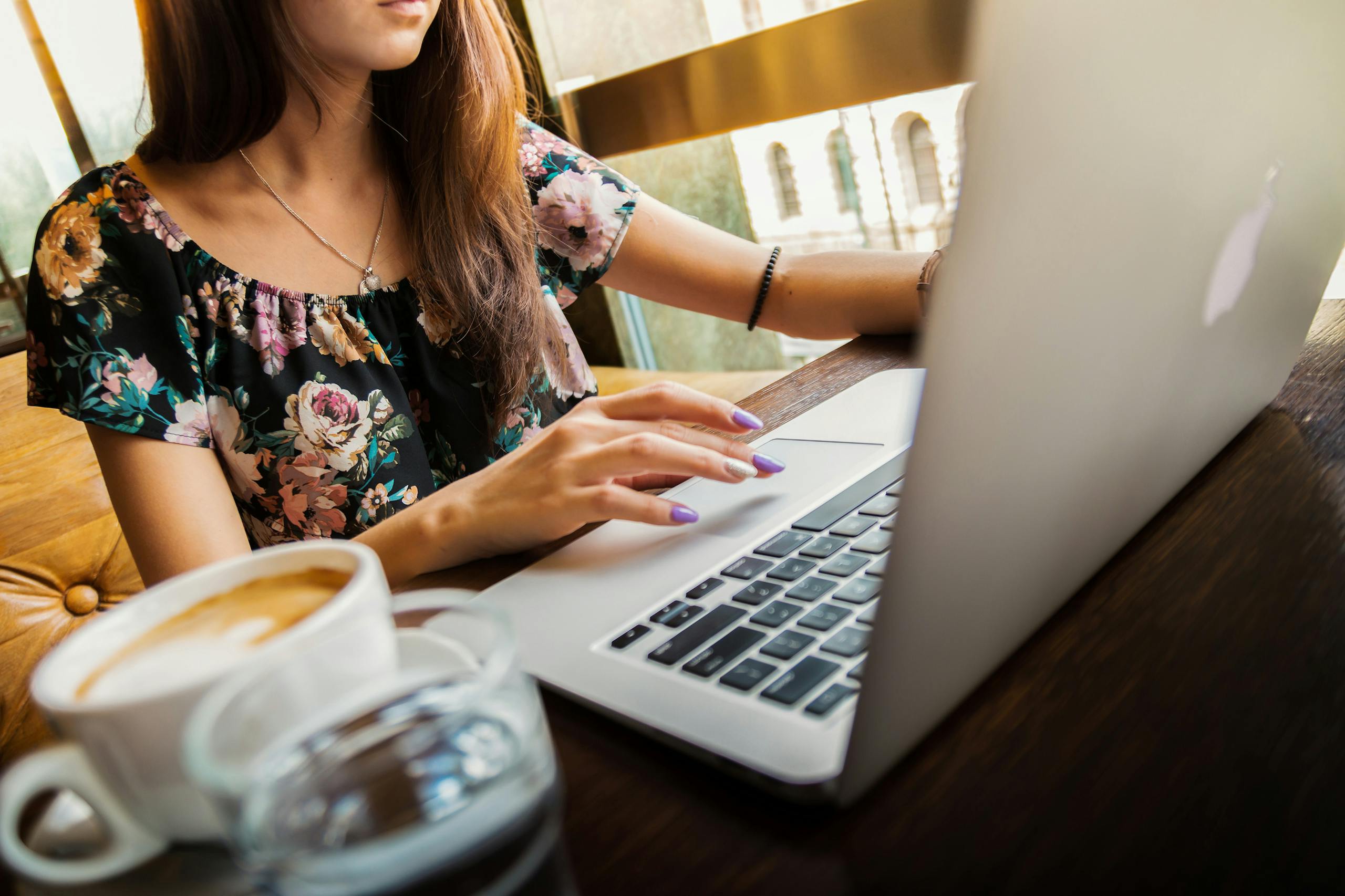 Woman working on laptop in café sipping coffee embodying modern remote work lifestyle.