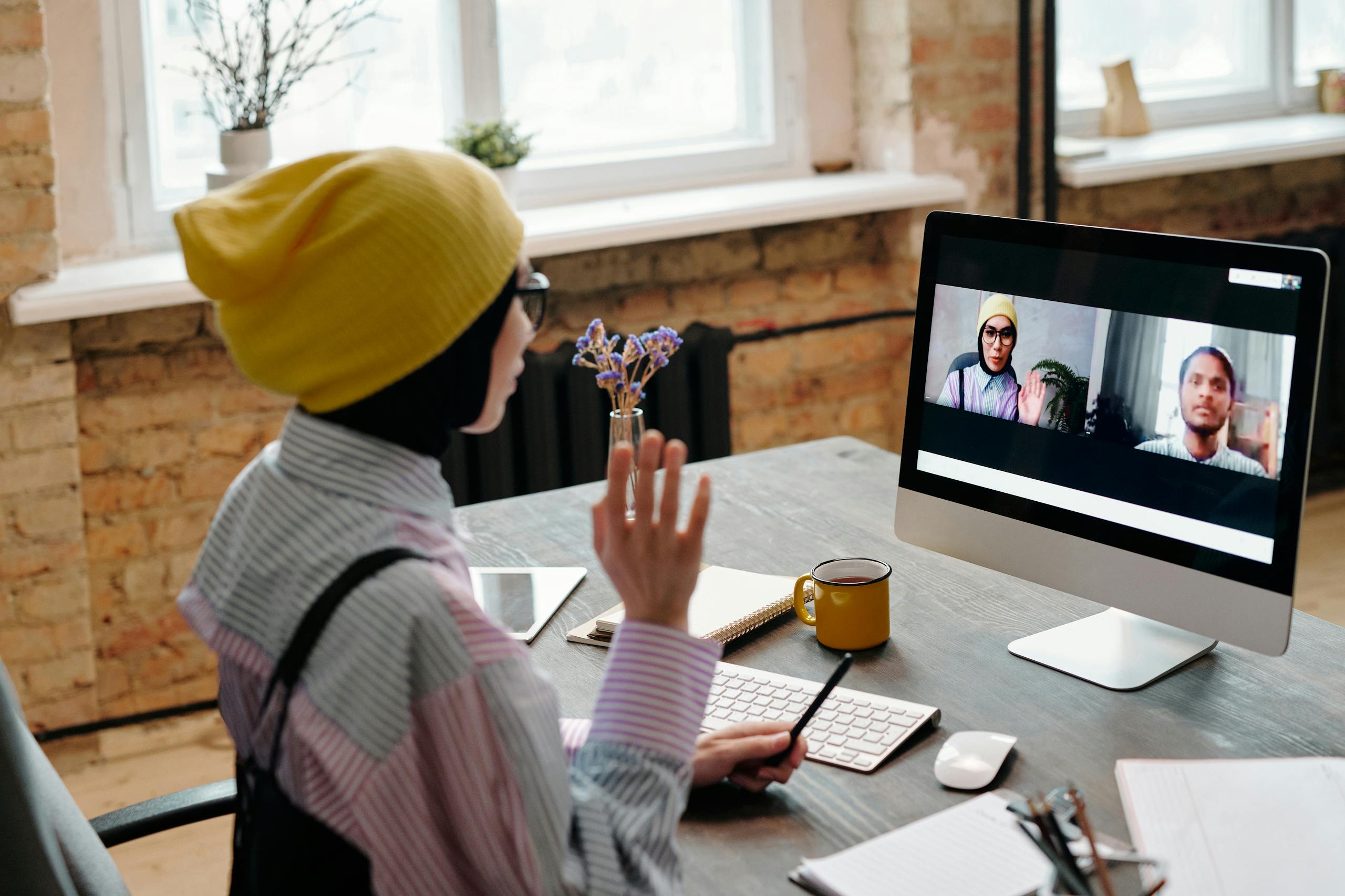 Adult woman engaged in video call meeting from cozy office environment showcasing remote work dynamics.