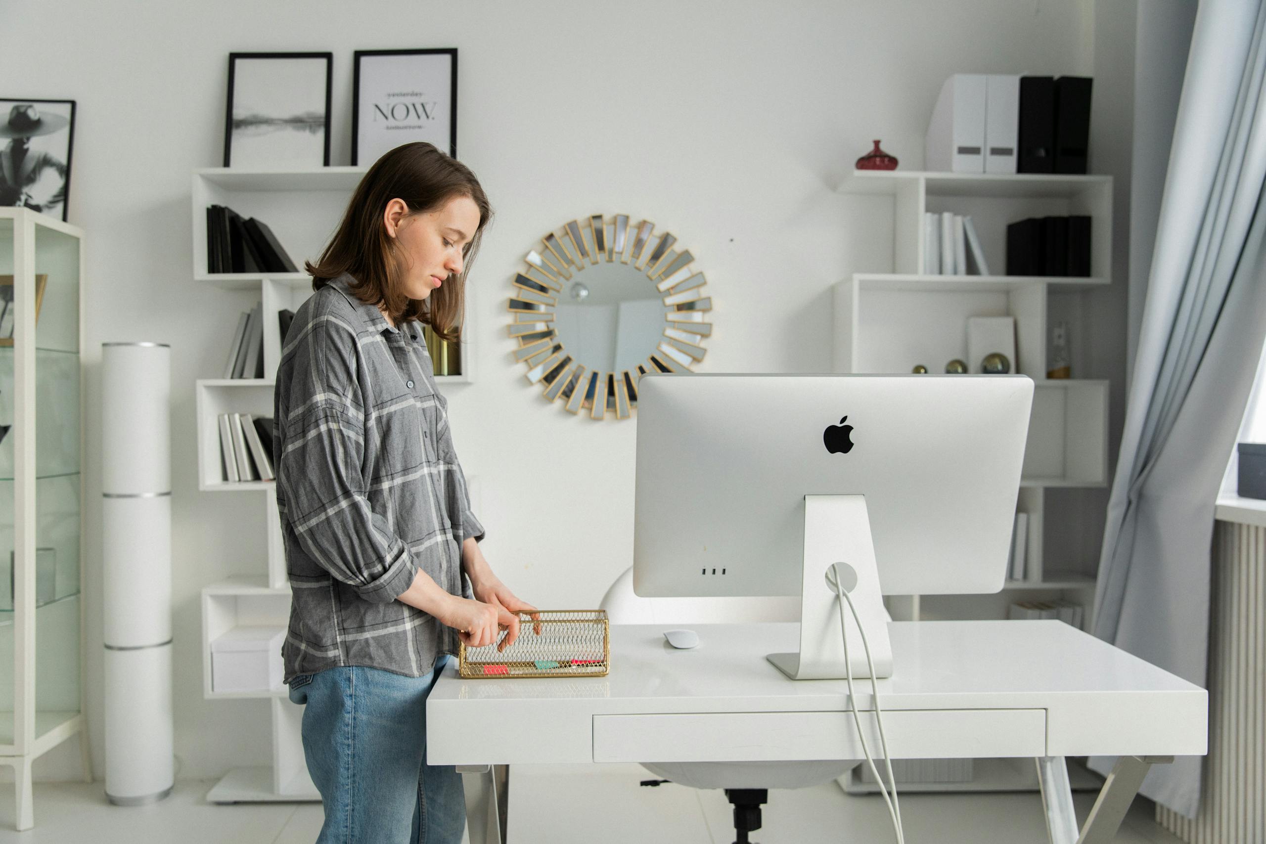 Woman organizing desk in modern stylish office with shelves
