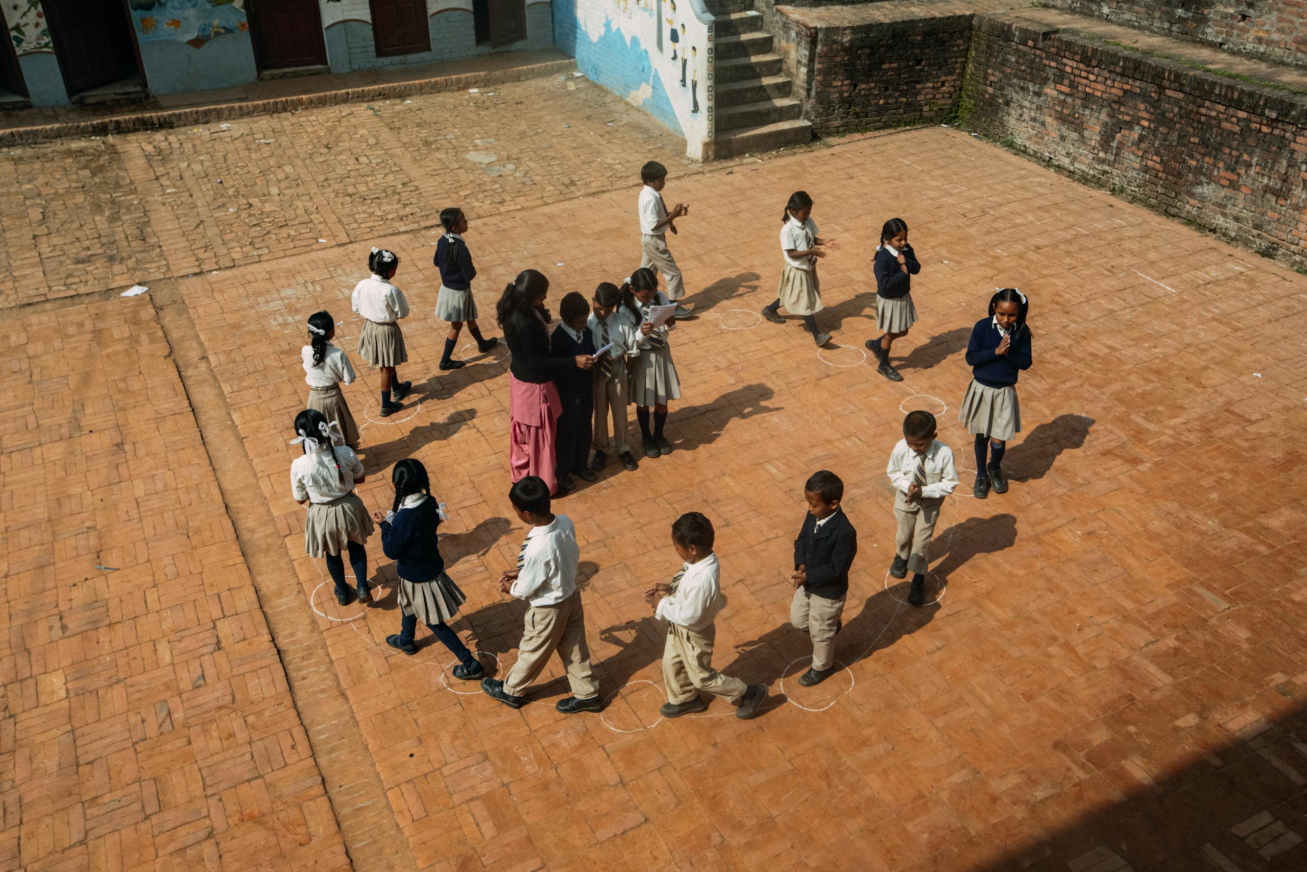 Aerial view of children playing a game on school courtyard during daytime.