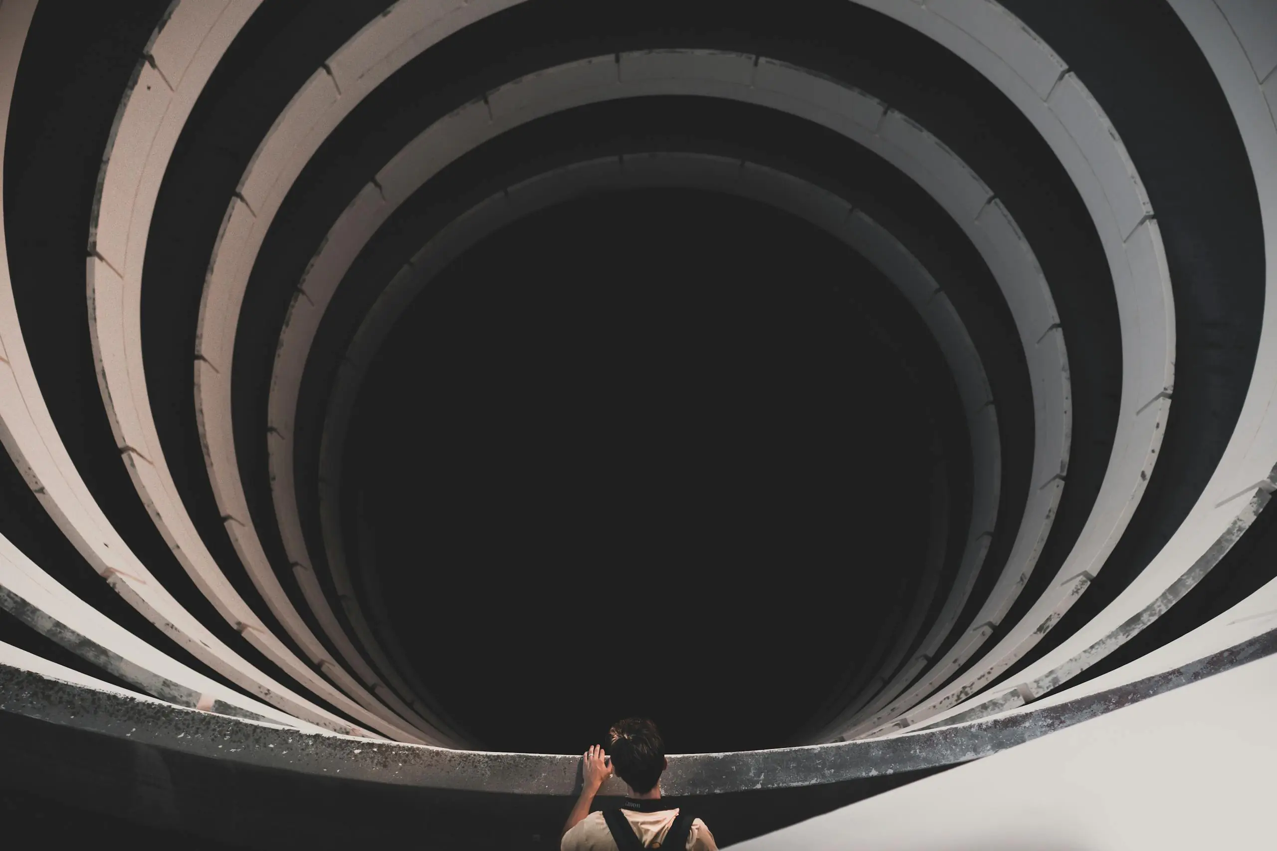 Person looking into spiral tunnel suggesting depth and mystery