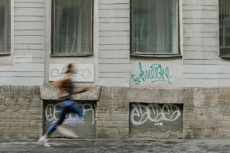 Woman running past urban graffiti wall with dynamic motion blur.