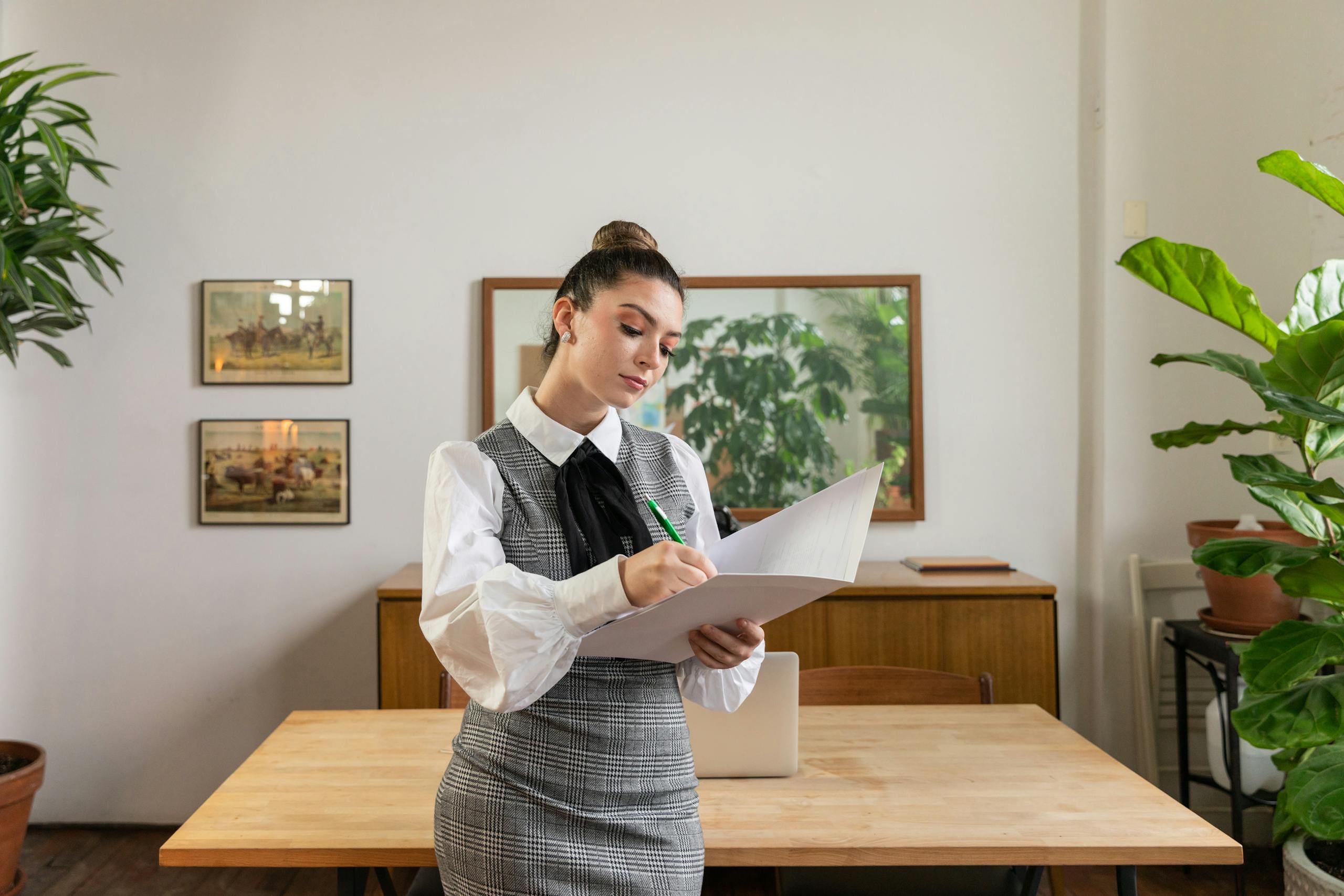 Businesswoman writing notes in stylish office with plants and decor