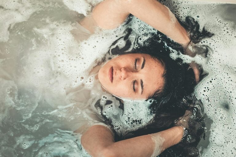 Relaxed woman enjoying peaceful bubble bath with eyes closed in calm moment