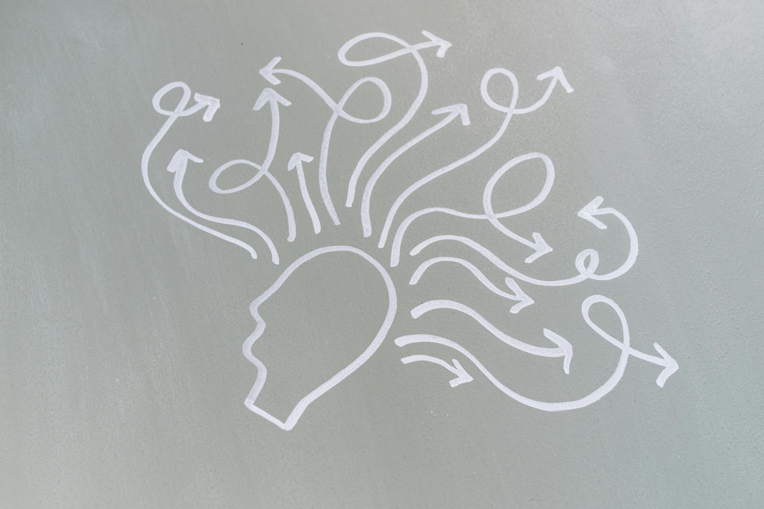 Chalk drawing of head with swirling arrows represents mental activity and thought process