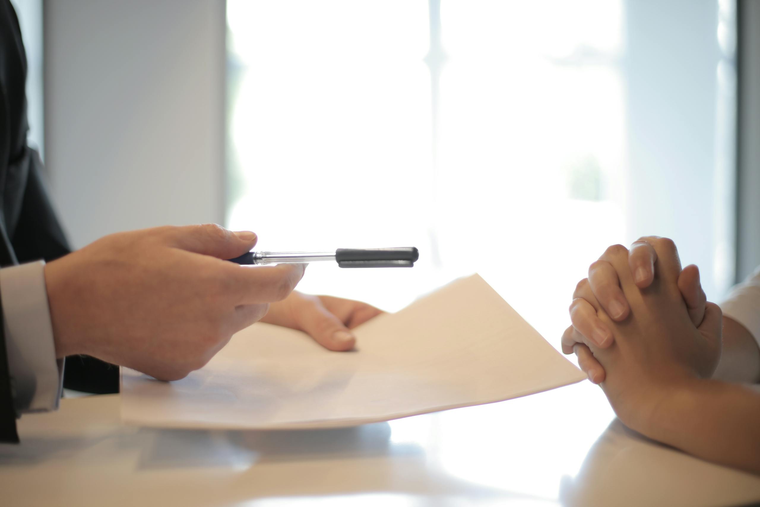 Close-up of contract signing with hands over documents in professional business interaction