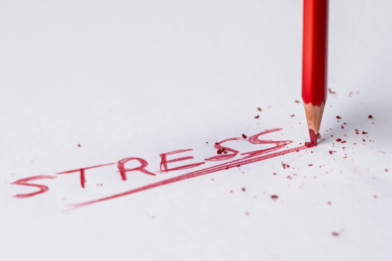 Close-up of red pencil writing stress on paper symbolizing pressure.