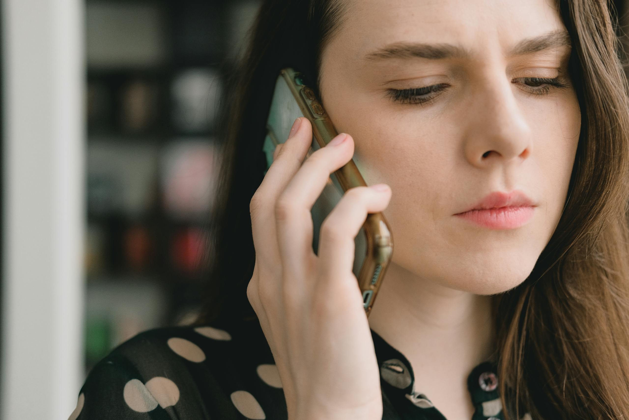 Close up of woman engaged in phone conversation indoors depicting thoughtful expression