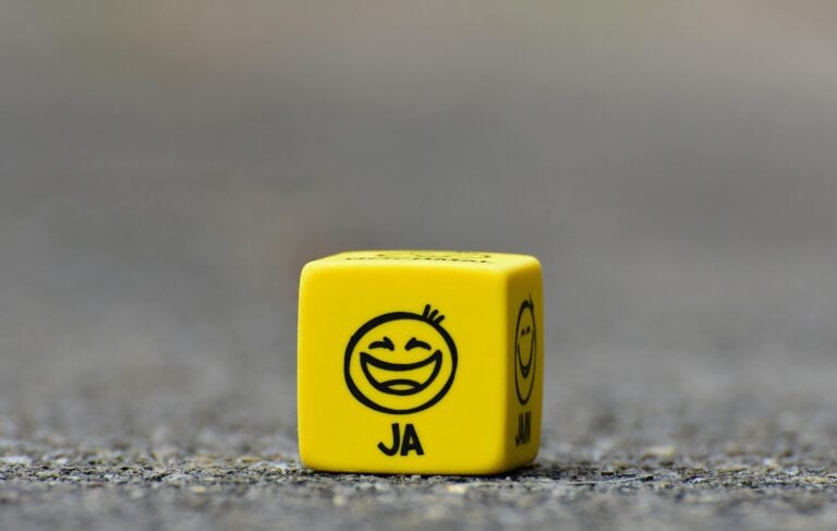 Close-up of yellow dice featuring smiley face emoticon symbolizing happiness.