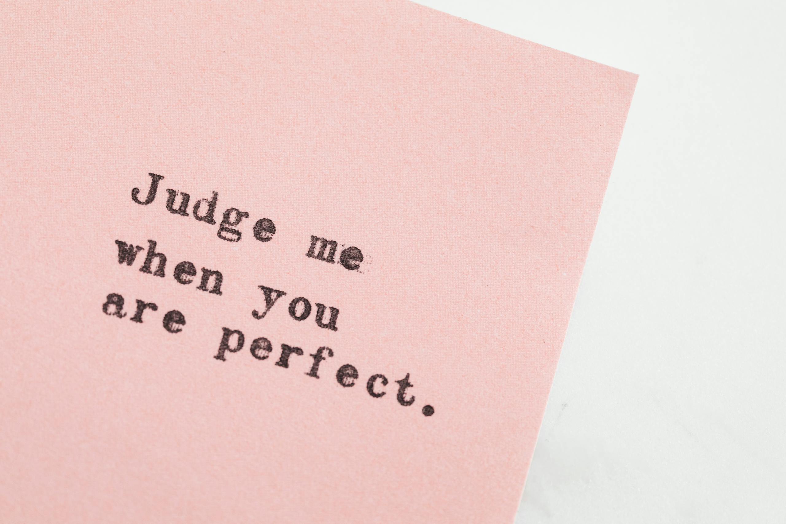 Inspirational quote on pink paper about judgment and perfection message