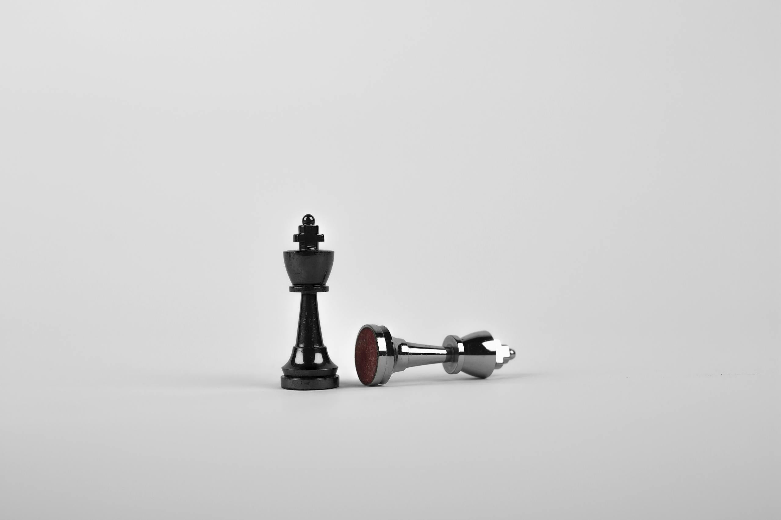 Chess king piece standing with fallen piece symbolizing strategy and victory.