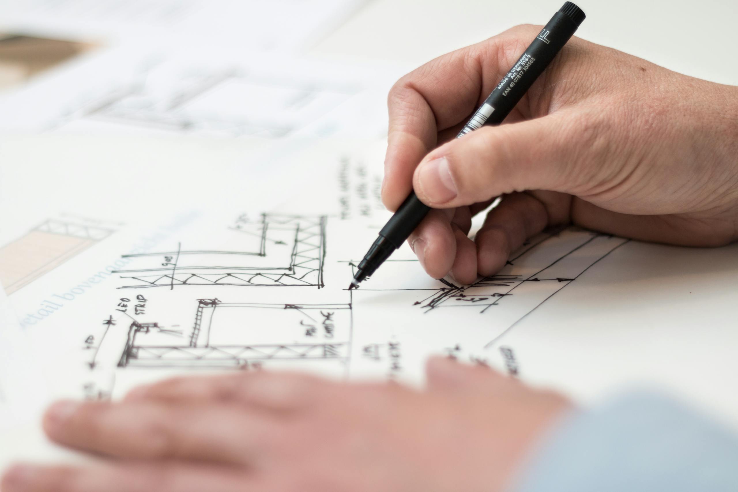 Close-up of hand drawing detailed technical blueprint designs with pen precision