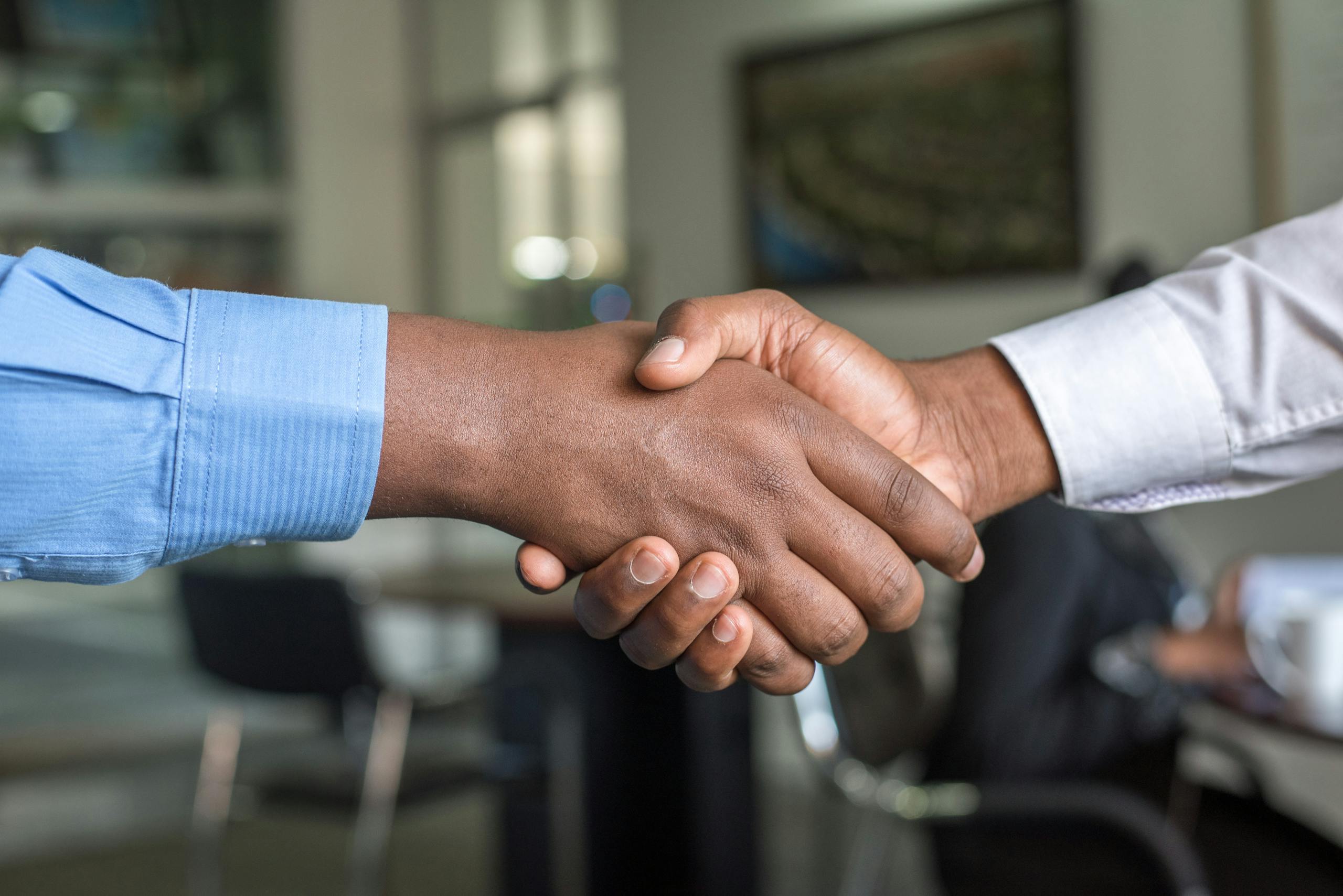 Close up of two mens handshake symbolizing agreement in office setting