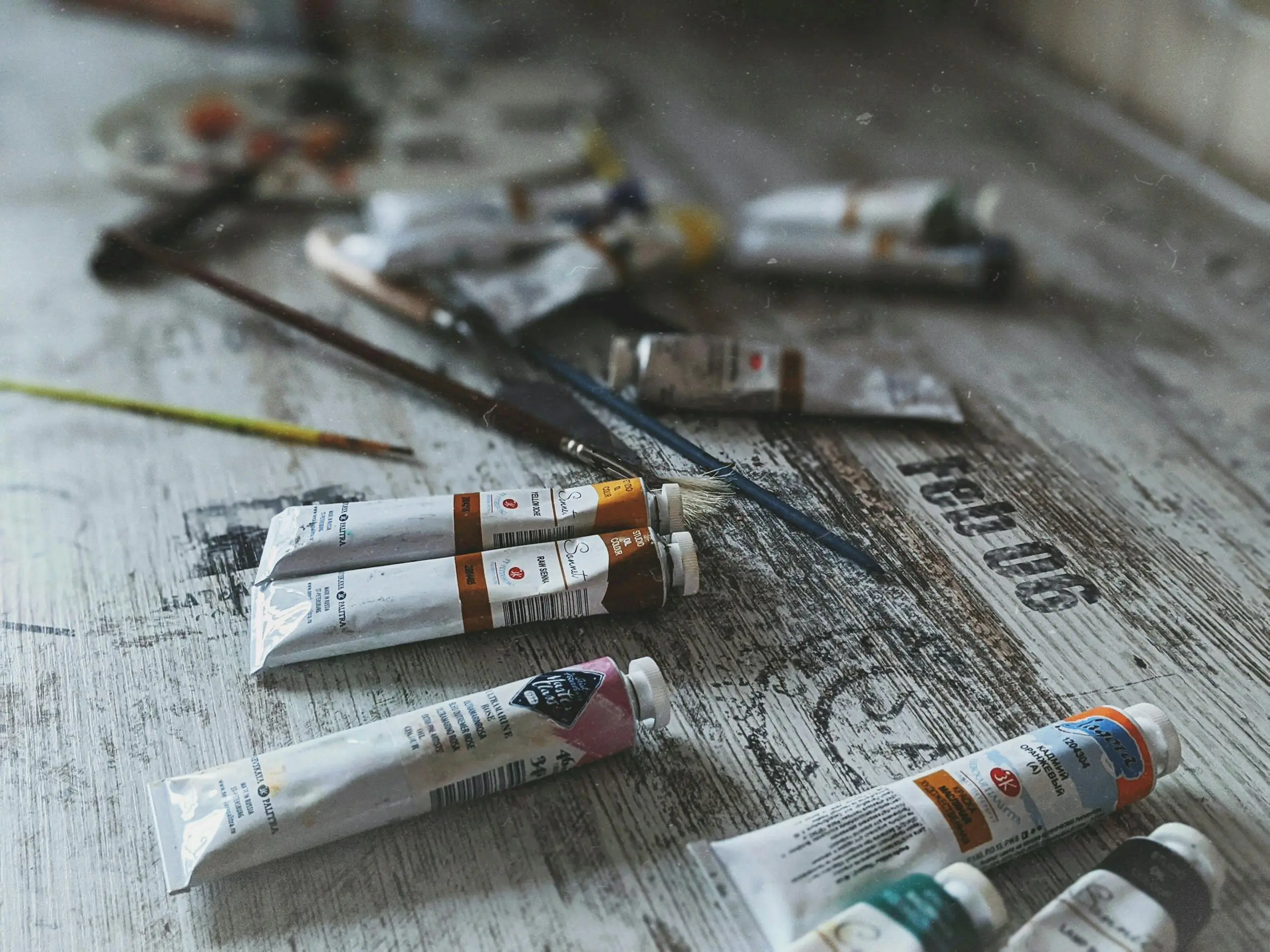 Close-up of acrylic paint tubes and artistic brushes on rustic wooden surface