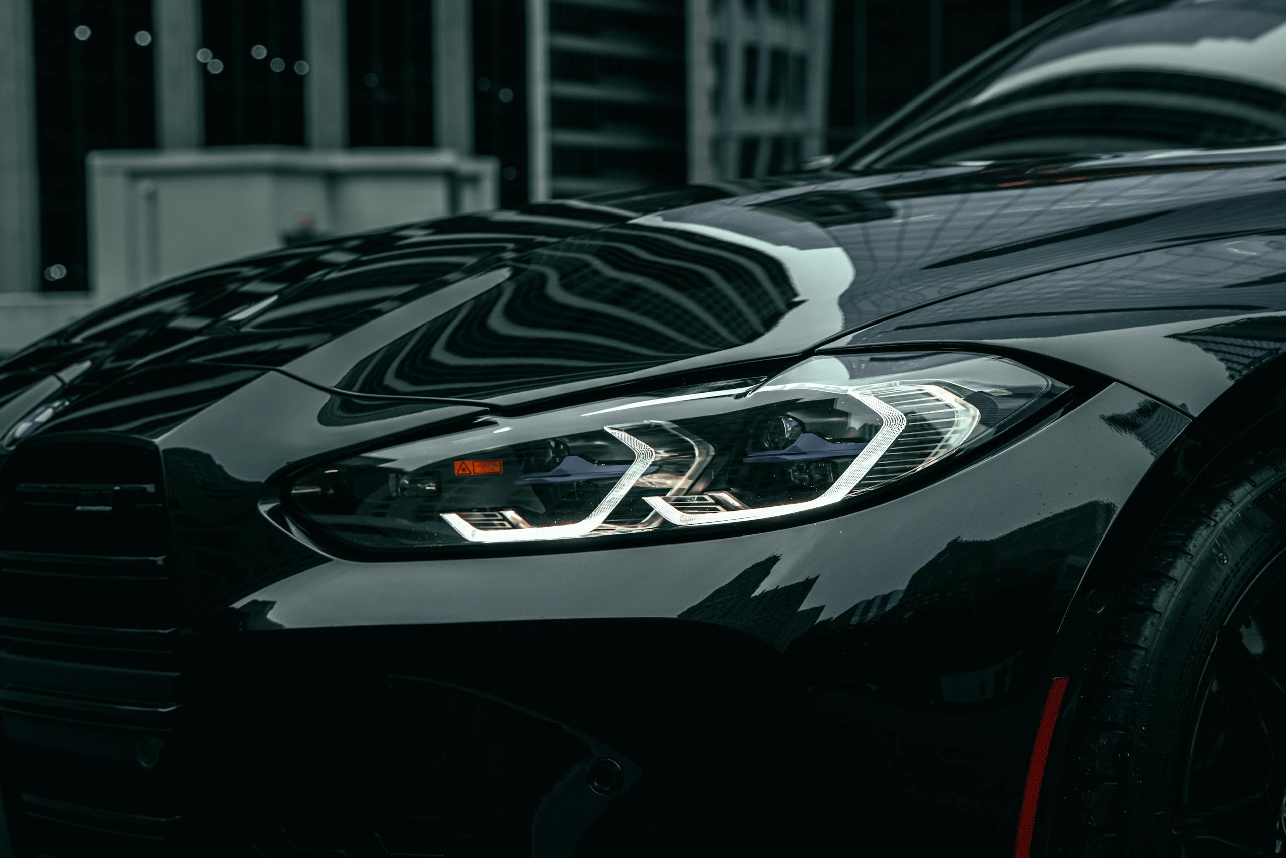Close-up of black BMW M3 headlight in downtown Chicago showcasing modern design