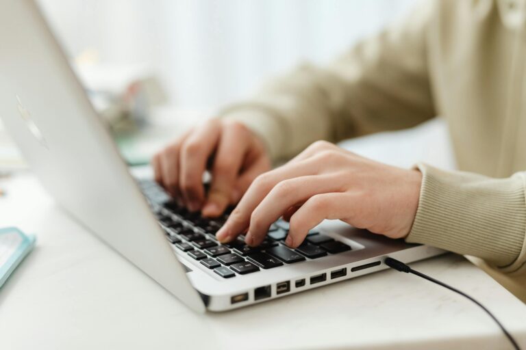 Close-up of hands typing on laptop keyboard indoors for technology and business themes.