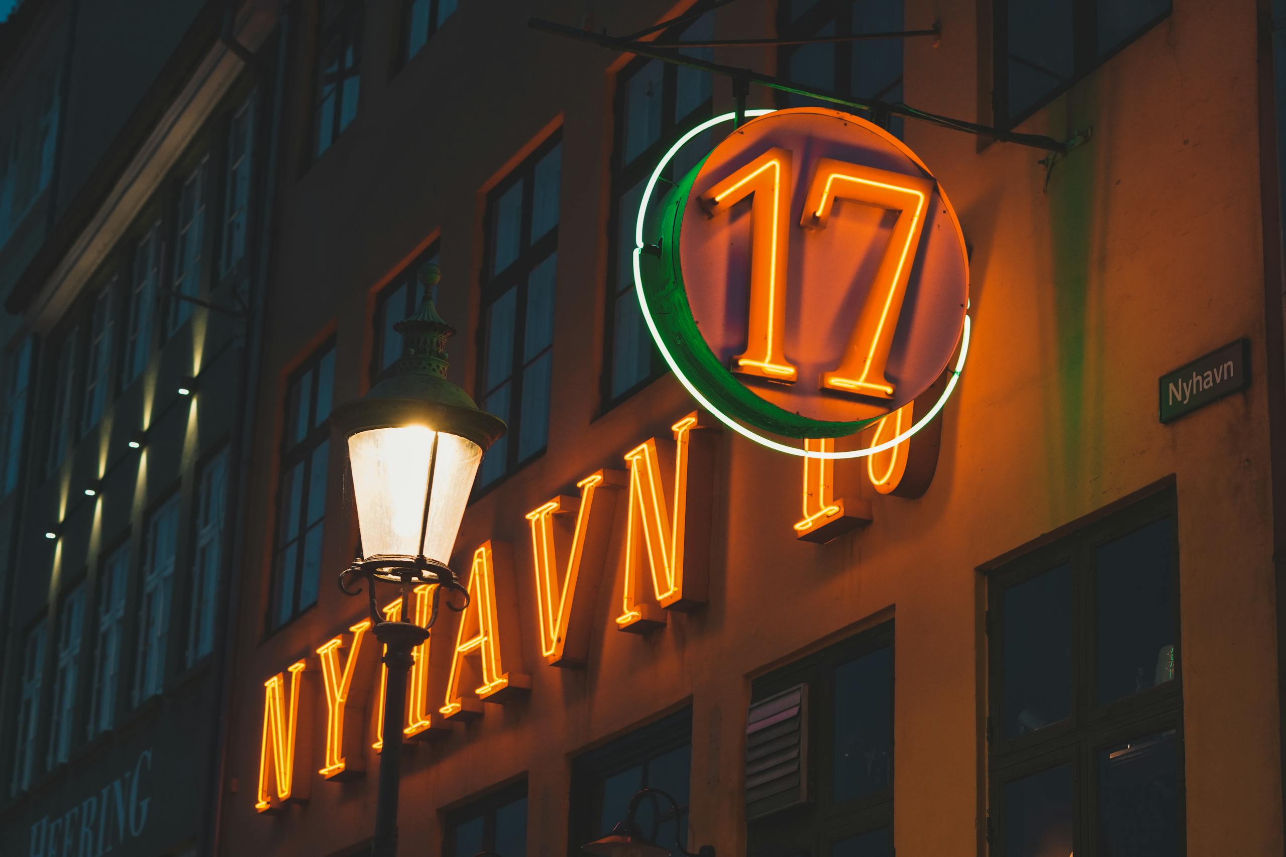Colorful neon signs illuminate historic Nyhavn district in Copenhagen, Denmark.