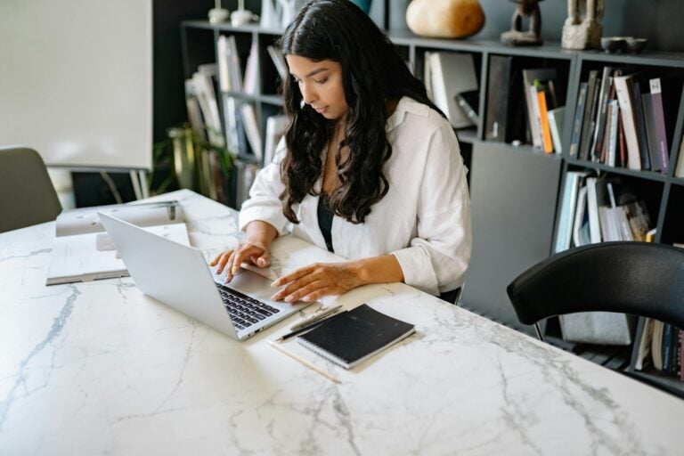 Confident businesswoman working on laptop in modern office setting.