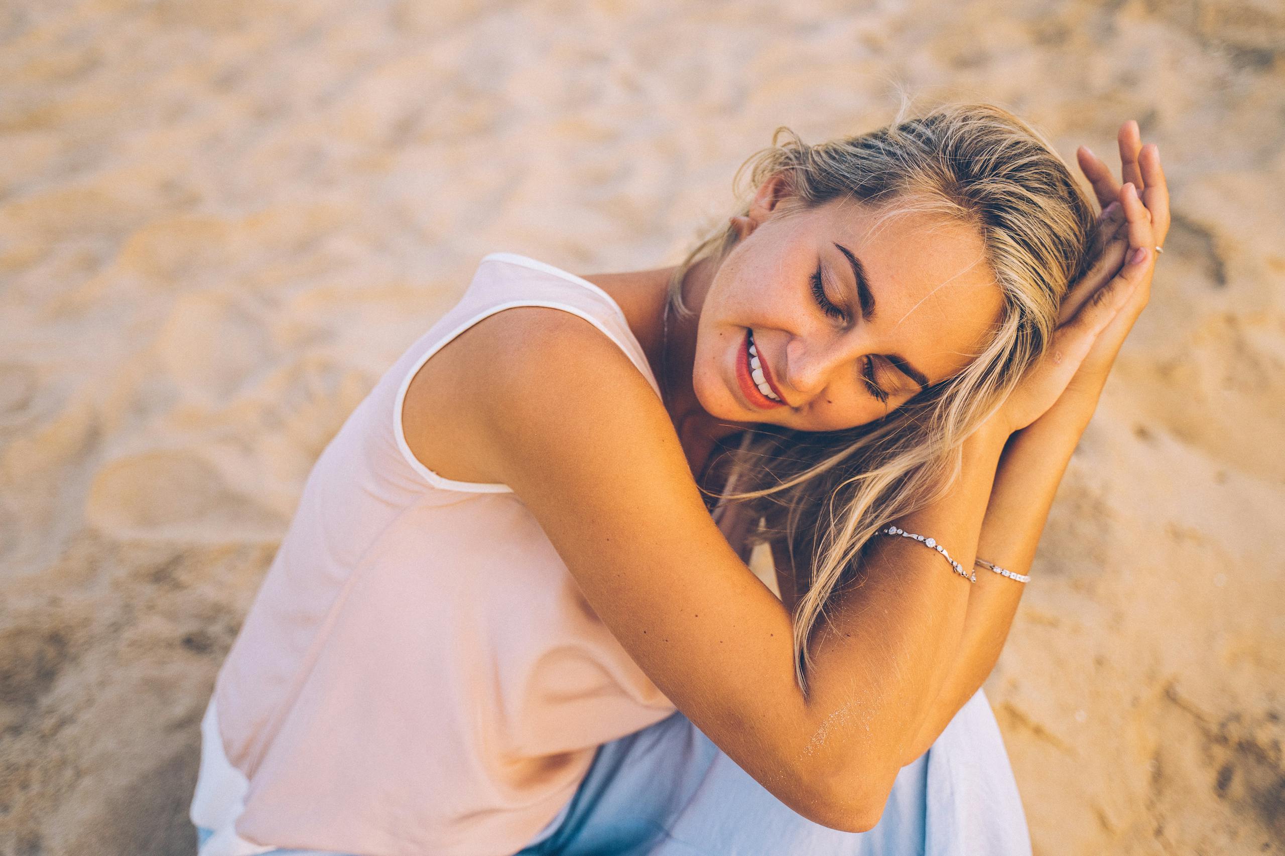 Content woman with closed eyes smiling peacefully on sunny beach