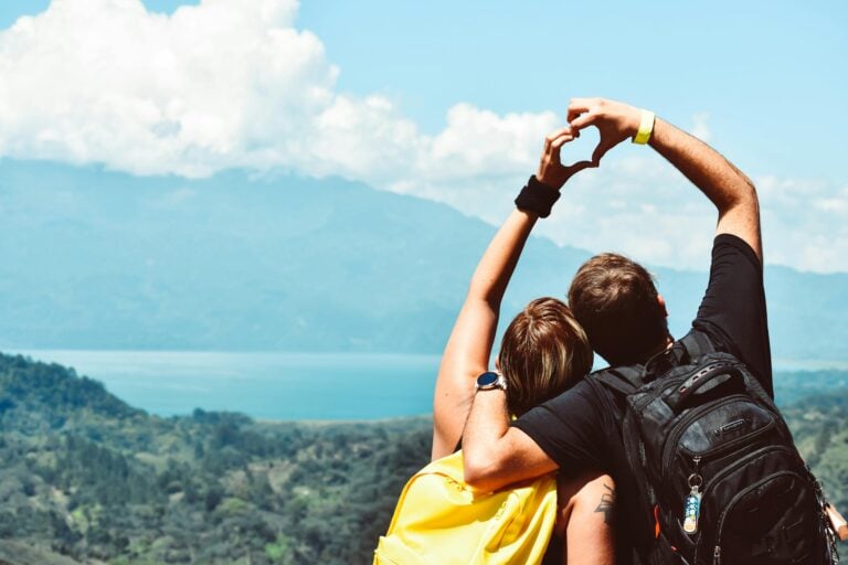 Couple making heart shape with arms over beautiful Honduras landscape view.