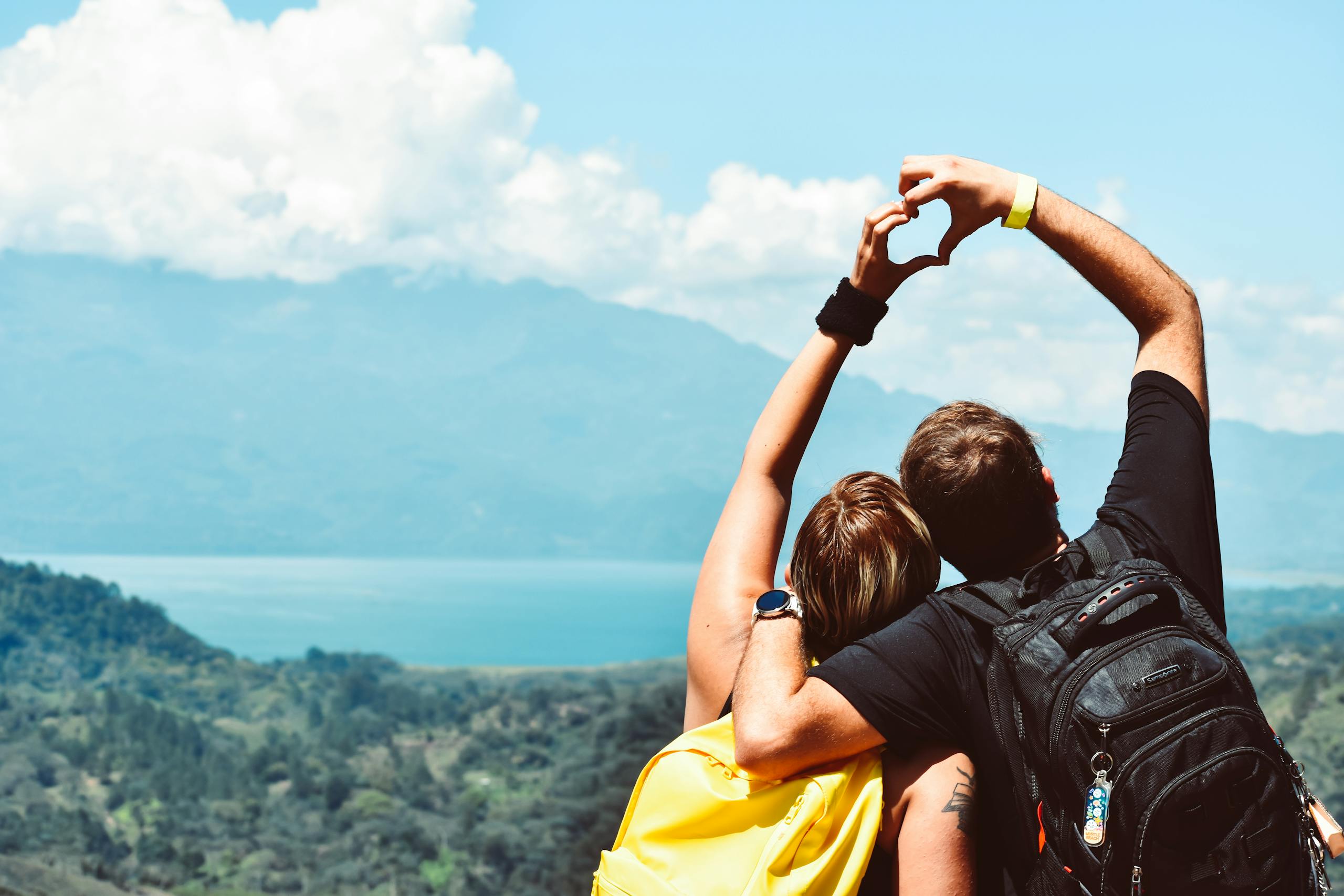 Couple making heart shape with arms over beautiful Honduras landscape view.