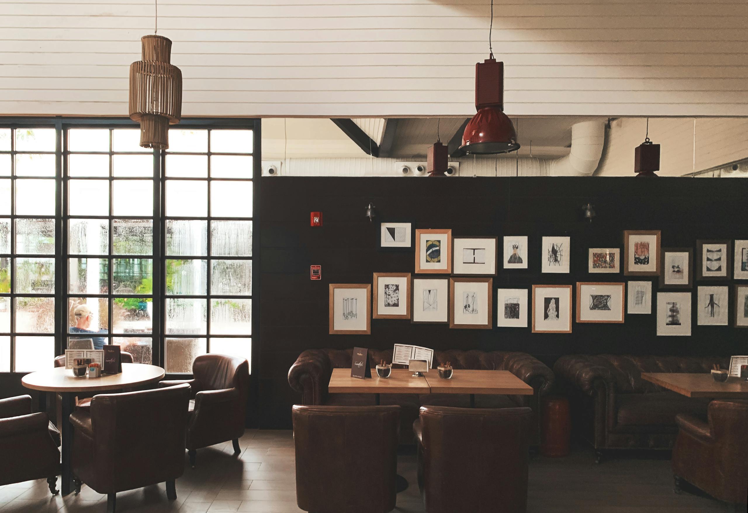 Cozy cafe interior with leather chairs, framed art, and pendant lighting