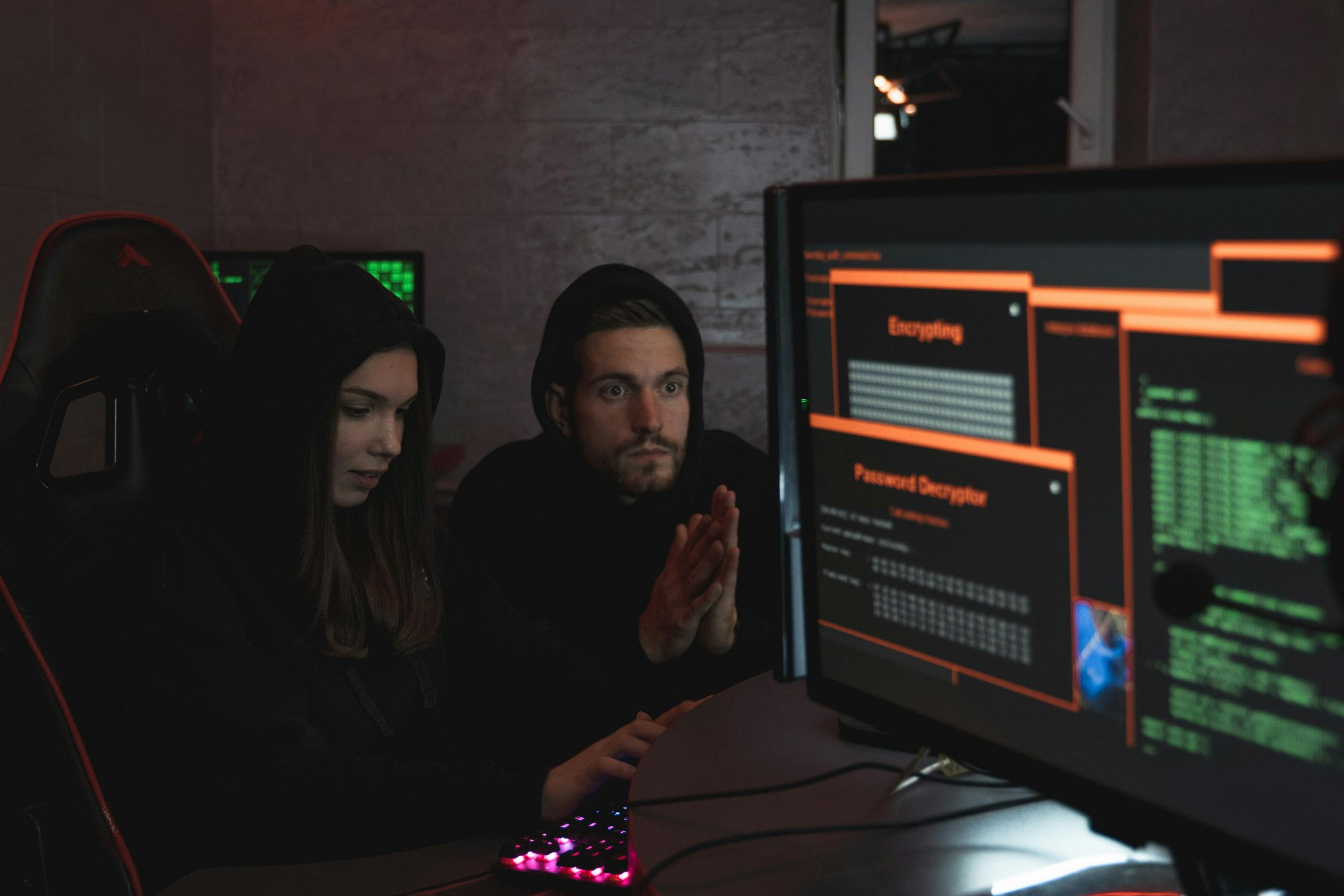 Cybersecurity experts in hoodies analyzing encrypted data on screens.