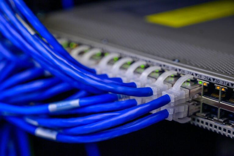 Blue ethernet cables connected to network switch in data center closeup.