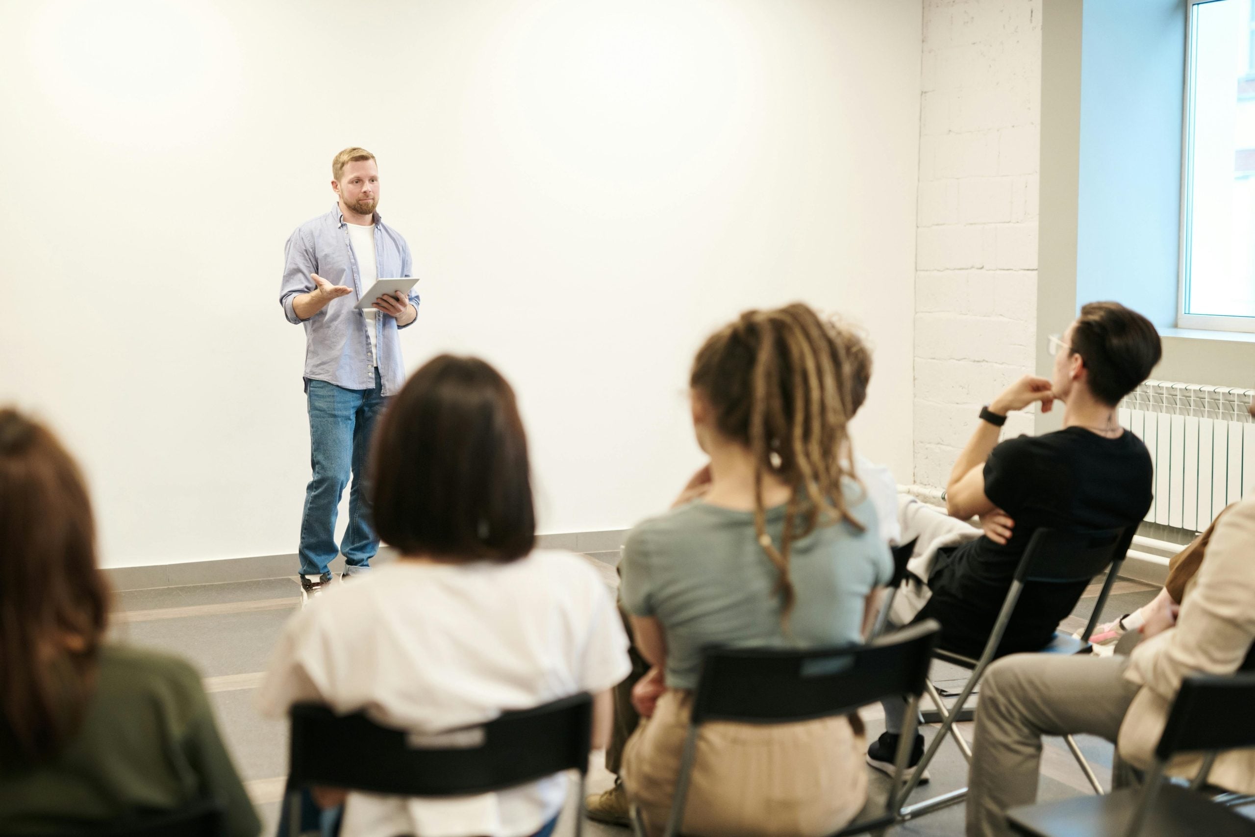 Man presenting to attentive group seated in casual circle formation