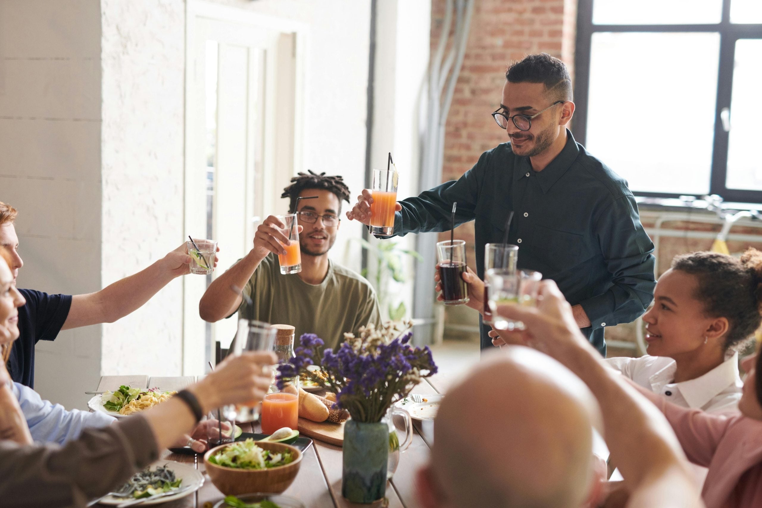 Group of diverse people toasting with colorful drinks at a social gathering